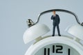 business or time countdown concept as miniature thinking businessman figure standing on white alarm clock