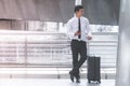 Business traveler with luggage is using his mobile phone Royalty Free Stock Photo