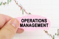 Against the background of the quote chart, a man holds a sign with the inscription - Operations Management Royalty Free Stock Photo