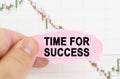 Against the background of the quote chart, a man holds a sign with the inscription - TIME FOR SUCCESS