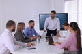 Business trainer near interactive board in meeting room during presentation