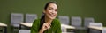 Business training. Young happy woman, female office worker sitting at desk in the office and smiling, listening to coach Royalty Free Stock Photo