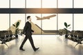 Business travel concept with man in black suit walking in waiting area hall in the airport with plane taking off through panoramic Royalty Free Stock Photo