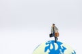 Business Travel and Global Concept. Close up of businessman traveler miniature figure with baggage running on mini world ball on