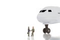 Business trip or agreement and success concept. Two miniature businessmen shaking hands near airplane ir aircraft on whit Royalty Free Stock Photo