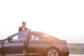 Businesswoman talking on mobile phone while disembarking from car against sky