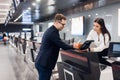 Business trip. Handsome young businessman in suit holding his passport and talking to woman at airline check in counter