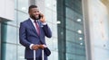 Business trip. Happy manager speaking on phone and holding a suitcase in airport Royalty Free Stock Photo