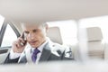 Mature executive talking on smartphone in car