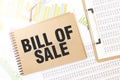 Business up graph on a sheet of craft colour Notepad with BILL OF SALE sign. Notepad on desk with financial documentation