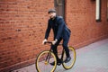 Business on wheels. Stylish confident businessman ride with his bicycle at building brick wall