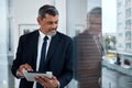 Business, window and senior man with a tablet, thinking and connection with network, inspiration or digital planning Royalty Free Stock Photo