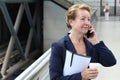 Business woman in the airport or train subway metro station making a phone call with smartphone Royalty Free Stock Photo