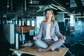 Business woman alone sitting at desk in her office, female employee meditating in lotus position Royalty Free Stock Photo