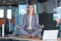 Business woman alone sitting at desk in her office, female employee meditating in lotus position Royalty Free Stock Photo