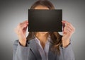 Business woman with black blank card over face against grey background Royalty Free Stock Photo