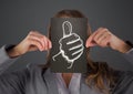 Business woman with black card over face showing white thumbs up doodle against grey background Royalty Free Stock Photo