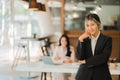 A business woman in a black suit looks good standing at her desk in a modern office. and colleagues working behind the scenes Royalty Free Stock Photo
