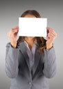 Business woman with blank card over face against grey background Royalty Free Stock Photo