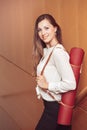 Business woman with blue eyes in white blouse shirt and black pants holding, carrying yoga mat in office Royalty Free Stock Photo