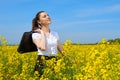 Business woman with briefcase relaxing in flower field outdoor under sun. Young girl in yellow rapeseed field. Beautiful spring la Royalty Free Stock Photo