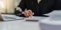 Business woman calculating monthly expenses, managing budget. Woman sitting at table using calculator to calculate tax