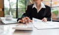 Business woman calculating monthly expenses, managing budget. Woman sitting at table using calculator to calculate tax