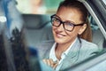 Business woman in car. Cheerful middle aged lady wearing eyeglasses sitting on back seat in the taxi, looking at camera Royalty Free Stock Photo