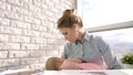 Business woman care baby at light window. Working mom with child at office