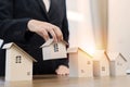 Business woman choosing mini wood house model from model on wood table, Planning to buy property