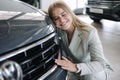 Business woman chossing a new car in a car showroom. Happy female hug new car and very glad Royalty Free Stock Photo