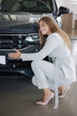 Business woman chossing a new car in a car showroom. Happy female hug new car and very glad Royalty Free Stock Photo