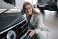 Business woman chossing a new car in a car showroom. Happy female hug new car and very glad. Elegant female in suit Royalty Free Stock Photo