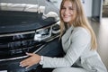 Business woman chossing a new car in a car showroom. Happy female hug new car and very glad Royalty Free Stock Photo