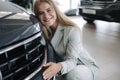 Business woman chossing a new car in a car showroom. Happy female hug new car and very glad Royalty Free Stock Photo