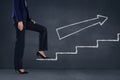 Business woman climbing stairs against blue background with white arrow Royalty Free Stock Photo