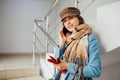 Business woman in coat stands on the stairs in the mall with smartphone. Shopping. Fashion