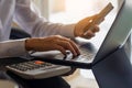 Accountant hand using mobile smart phone and laptop computer with calculator on the table Royalty Free Stock Photo