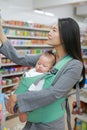 Business woman in Convenience Store while carrying her baby boy by hipseat Royalty Free Stock Photo