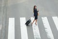 Business woman crossing street with travel bags