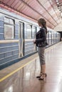 Business woman with a cup of coffee at subway station and train. Beautiful girl in sunglasses and a jacket at the subway station. Royalty Free Stock Photo