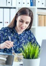 Business woman eating lunch at her workplace looking at the laptop screen. Folders with documents in the foreground Royalty Free Stock Photo