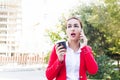 Business woman emotionally talking on the phone and holding coffee in outdoor