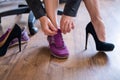 A business woman exchanges high heels for comfortable shoes in the workplace. A close-up of female hands takes off her