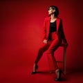 Business Woman Fashion. Elegant Lady in Red Pant Suit with Bob Hairstyle wearing Black Eyeglasses side view. Stylish Model in Royalty Free Stock Photo