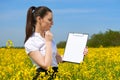 Business woman in flower field outdoor read clipboard. Young girl in yellow rapeseed field. Beautiful spring landscape, bright sun Royalty Free Stock Photo