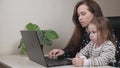 Business woman freelancer works at home with a laptop with a small child, mom types text on a computer keyboard with a Royalty Free Stock Photo