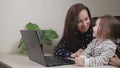 Business woman freelancer works at home with a laptop with a small child, mom types text on a computer keyboard with a Royalty Free Stock Photo