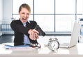 Business woman furious and angry working with computer laptop pointing gun to alarm clock