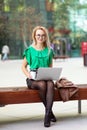 Business Woman with glasses sitting on bench outside street park business district drinking coffee and working on laptop Royalty Free Stock Photo